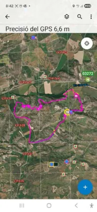 Captura de pantalla d'un mòbil amb l'aplicació Field Maps sobre una ortofoto de terreny agrícola i forestal. A la part superior s'indica «Precisió del GPS 6,6 m». Sobre el mapa es veu el perímetre d'un incendi forestal dibuixat amb una línia magenta, la icona d'un vehicle etiquetat «03272» i la posició pròpia, a més de rètols de camins i diversos símbols de recursos. Mostra com el SIG permet veure en temps real la localització dels recursos i el perímetre de l'incendi.
